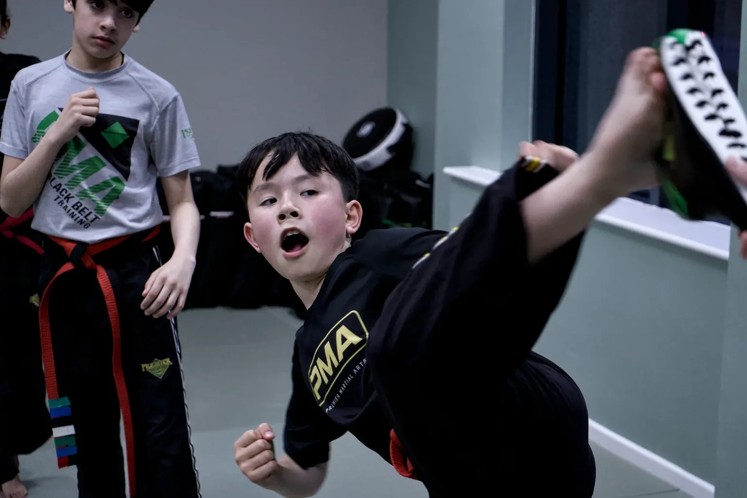 A young boy in a PMA uniform throwing a high kick